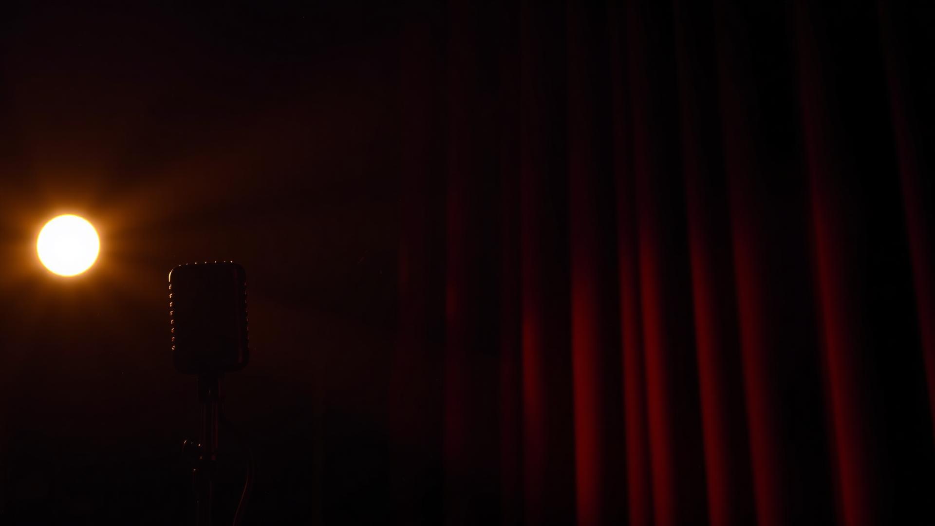 Sala teatrale scura con microfono vintage illuminato da luce calda laterale